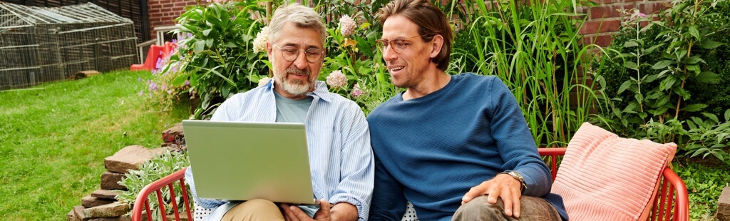 Ein Mann sitzt mit Laptop im Garten und erklärt einem anderen: Was ist WebDAV?